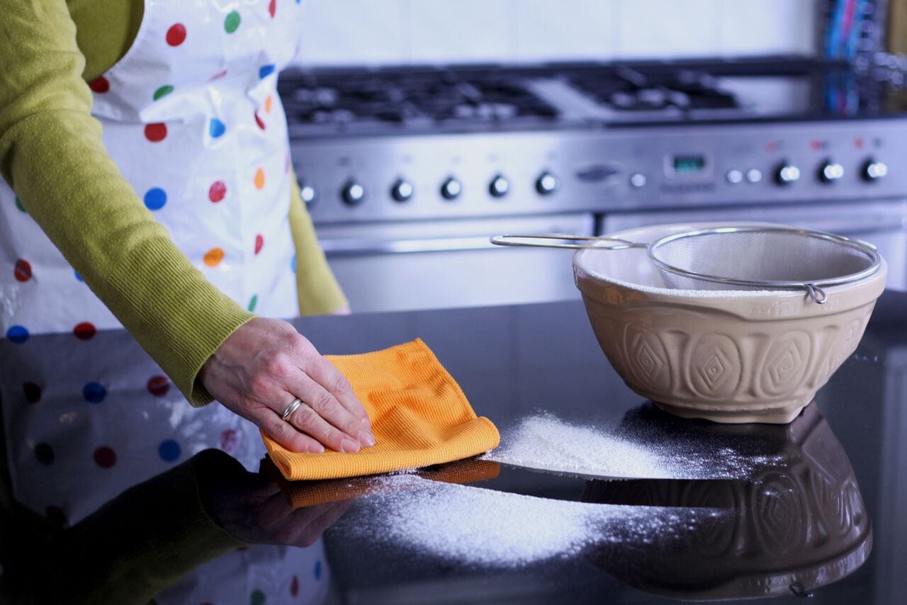 Wiping kitchen surface with orange cloth